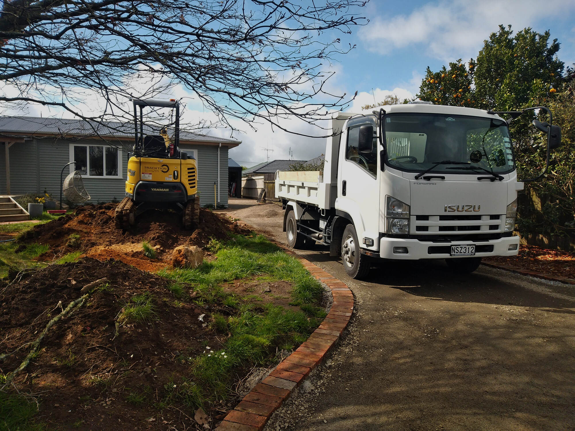 Mini excavator and tipper truck working a residential driveway